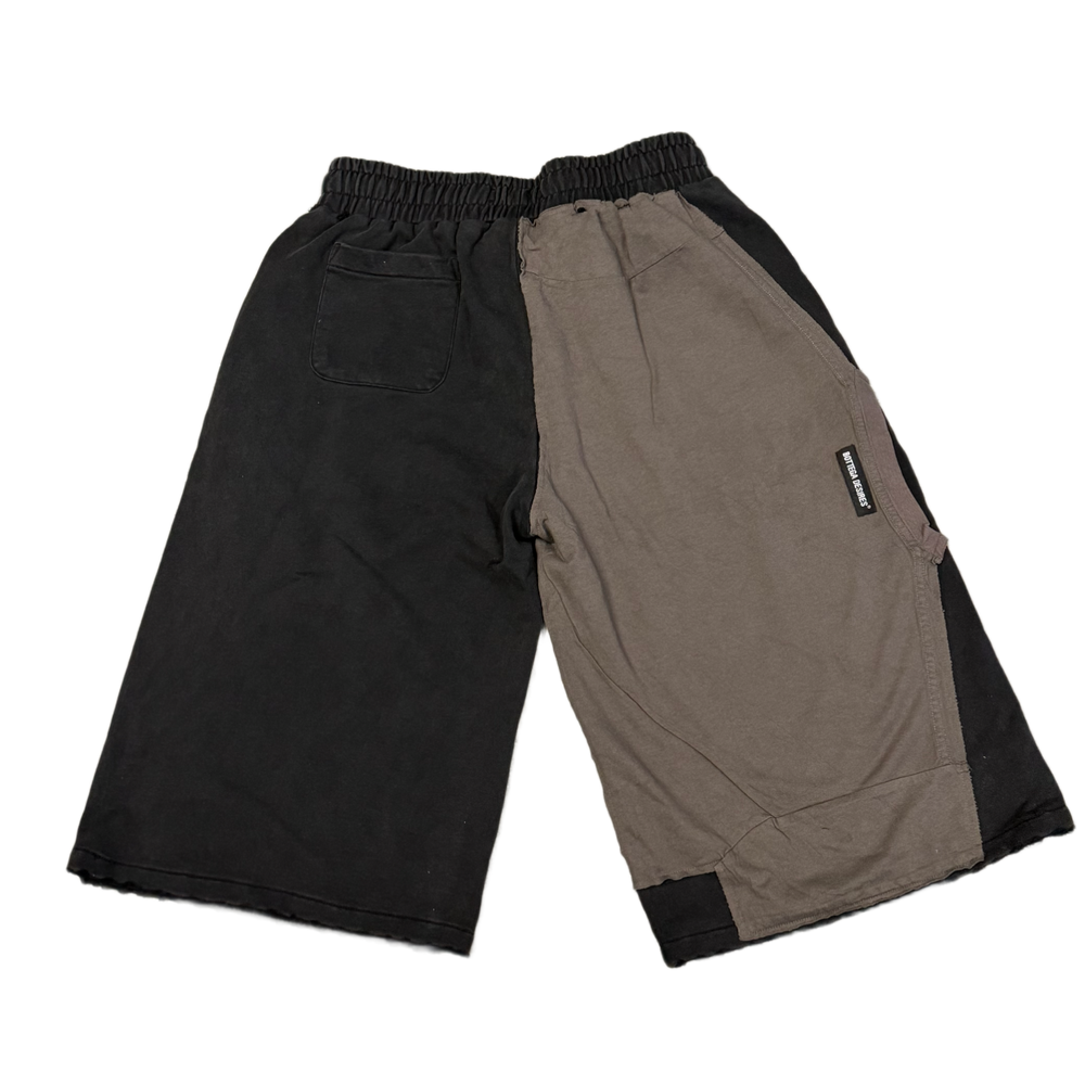 Back flat lay view of the Bottega Desires three-quarter sweat shorts, highlighting the multi-paneled cut-and-sew design with solid charcoal and black fleece segments divided down the center seat and legs.