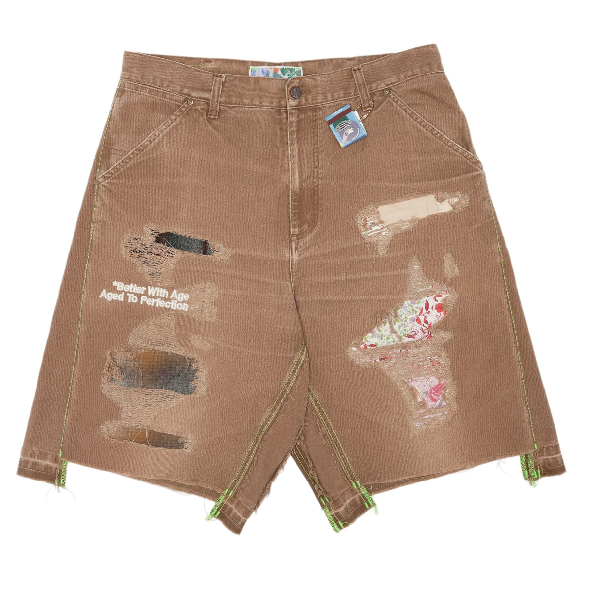 Front flat lay view of the Better With Age 'Double Wide' carpenter shorts in a heavily sun-faded chocolate brown duck canvas, showcasing a relaxed wide-leg workwear silhouette, classic utility pocket styling, multiple intentional raw-edge distressed holes on the thighs, hand-sewn patchwork repairs, and unique multi-colored contrast graphic transfers scattered across the front legs.