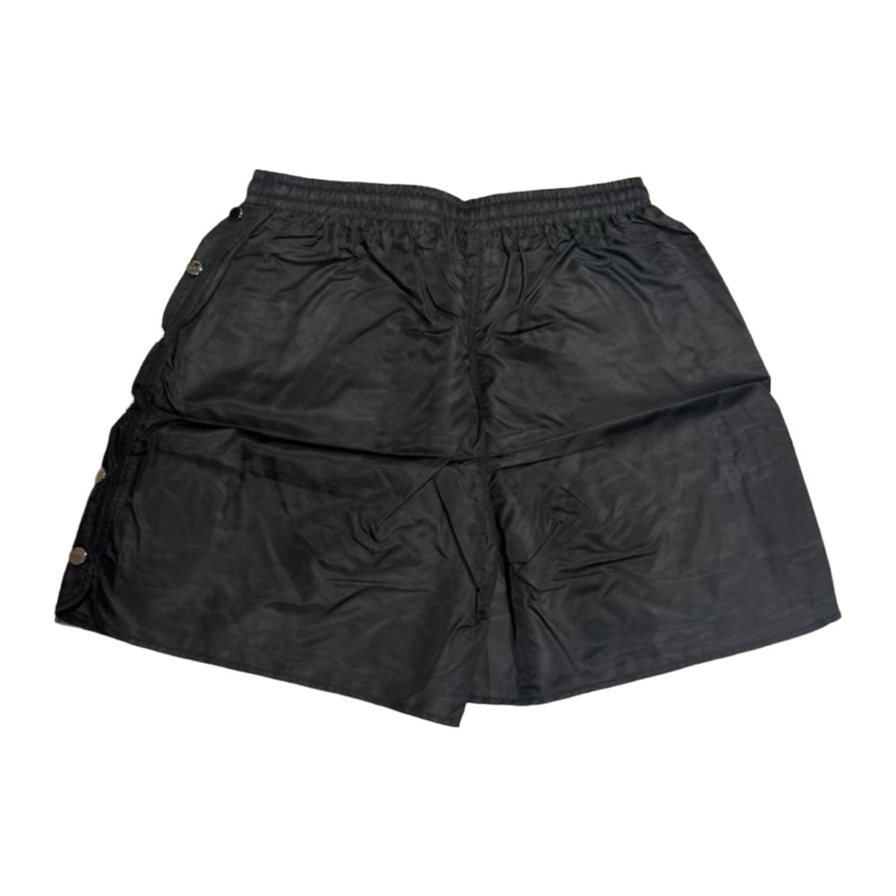 Back flat lay view of the black Saint Vanity technical nylon shorts, highlighting the lightweight athletic drape, a structured horizontal back yoke seam panel beneath the elastic waistband, and a clean, unadorned solid black reverse profile with subtle side-snap hardware visible at the margins.