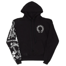 Front flat lay view of the Chrome Hearts 'Stencil Sleeve' hoodie in heavy black fleece, featuring an oversized drawstring hood, a white circular horseshoe monogram logo printed on the left chest, a split kangaroo pouch pocket, and a dense white stenciled cluster of signature gothic cross and scroll branding graphics running down the length of the right sleeve.