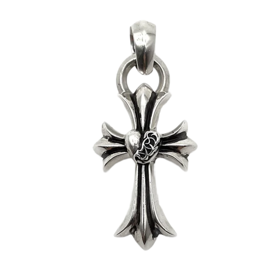 A detailed close-up studio layout view of the Chrome Hearts cross pendant, showcasing a solid sterling silver sculpted cross body with a striking oxidized antique finish, featuring a dimensional raised heart wrapped in intricate vine scrollwork at the central intersection, completed by a heavy integrated circular ring and polished top bale loop.