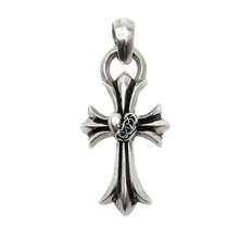 A detailed close-up studio layout view of the Chrome Hearts cross pendant, showcasing a solid sterling silver sculpted cross body with a striking oxidized antique finish, featuring a dimensional raised heart wrapped in intricate vine scrollwork at the central intersection, completed by a heavy integrated circular ring and polished top bale loop.