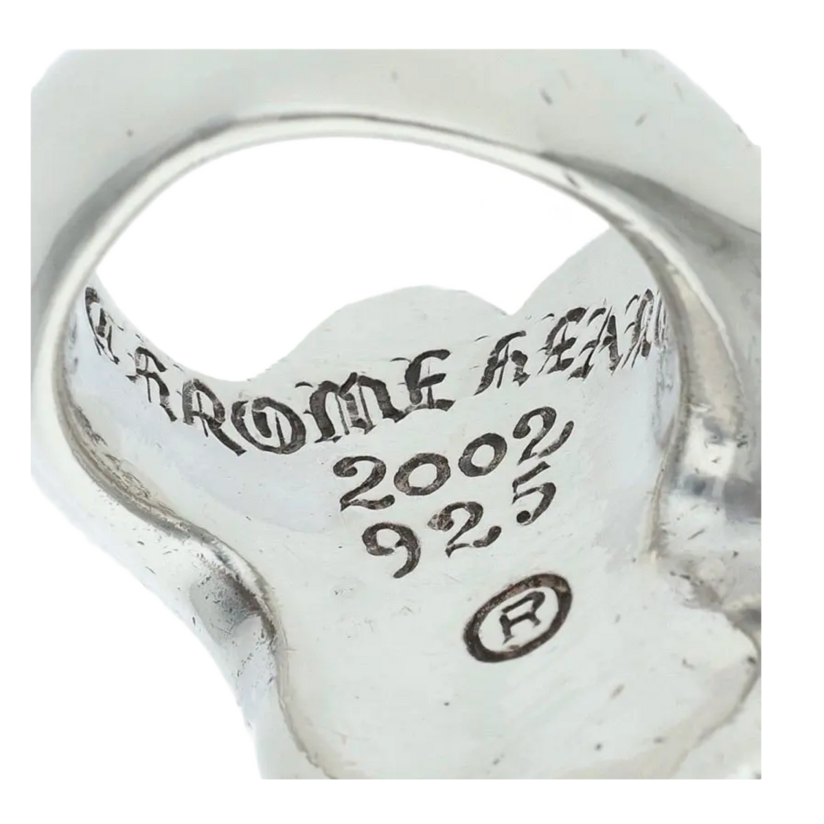 A macro close-up view looking directly into the textured inner band of the sterling silver ring, highlighting the authentic engraved circular framework featuring a gothic 'CHROME HEARTS' script stamp alongside a '2002' copyright date and a '.925' silver purity designation hallmark.