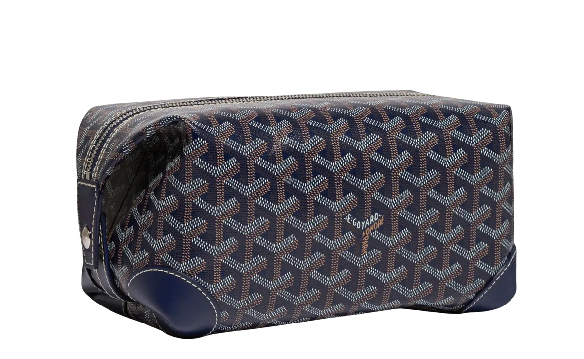 Front view of the Goyard Bowling 25 toiletry bag in navy blue coated canvas, featuring the iconic white, tan, and navy hand-painted Goyardine chevron print, structured leather piping along the edges, and a secure top zipper closure.