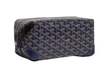 Front view of the Goyard Bowling 25 toiletry bag in navy blue coated canvas, featuring the iconic white, tan, and navy hand-painted Goyardine chevron print, structured leather piping along the edges, and a secure top zipper closure.