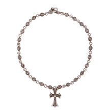 An overview of the Chrome Hearts 'Rose Ball' necklace arranged in a large circle against a plain background, showcasing a repeating chain of intricate, textured spherical beads anchored by a dangling central floral small cross pendant.
