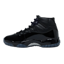 A clean lateral profile view of the all-black Jordan 11 x CDG sneaker against a dark background, showing the extended high-cut patent leather wrapping across a glossy Phylon midsole, accented by a white and black checkerboard carbon fiber shank plate beneath the arch.