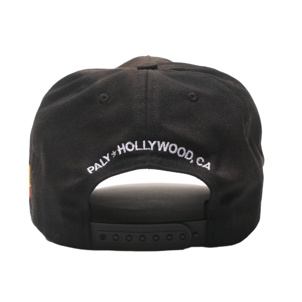 Back view of the Paly washed black hat, showcasing an adjustable fabric strap closure with a silver metal buckle, a curved rear opening, and white embroidered 'PALY HOLLYWOOD, CA' branding curved across the lower back panel.