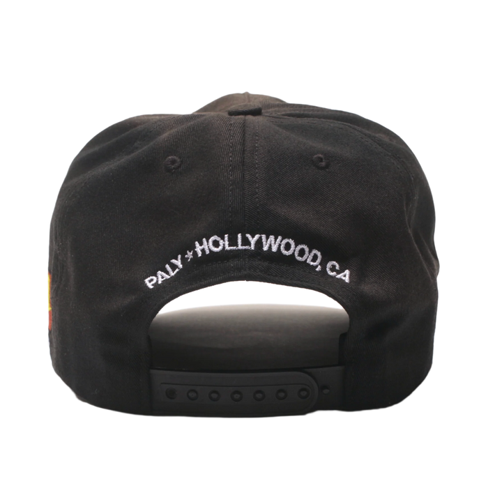Back view of the Paly washed black hat, showcasing an adjustable fabric strap closure with a silver metal buckle, a curved rear opening, and white embroidered 'PALY HOLLYWOOD, CA' branding curved across the lower back panel.