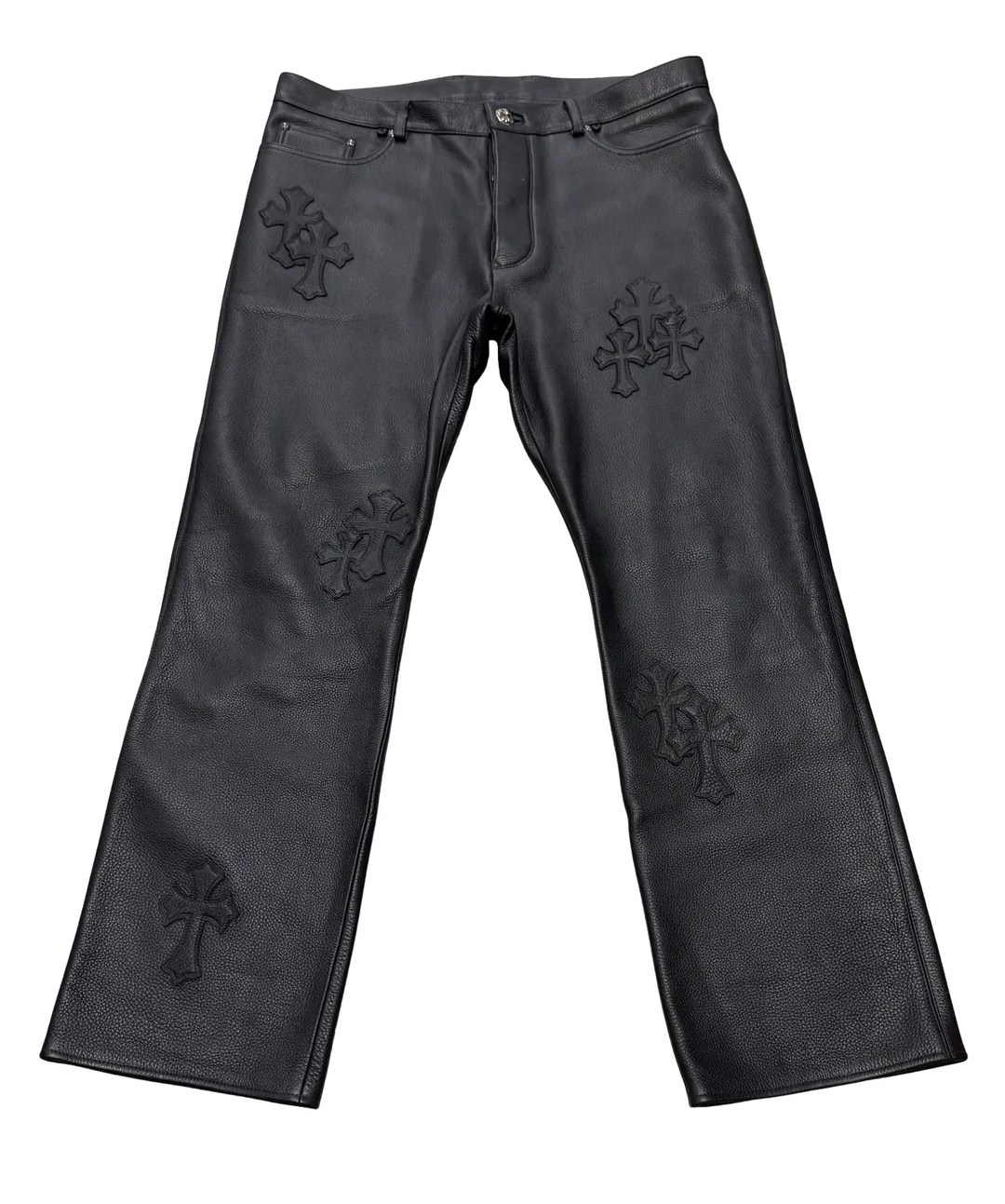 Front flat lay view of the Chrome Hearts custom leather pants in heavy pebbled black full-grain leather, showcasing a straight-leg silhouette, traditional five-pocket styling, and multiple stacked tonal black leather cemetery cross patches stitched across both legs.