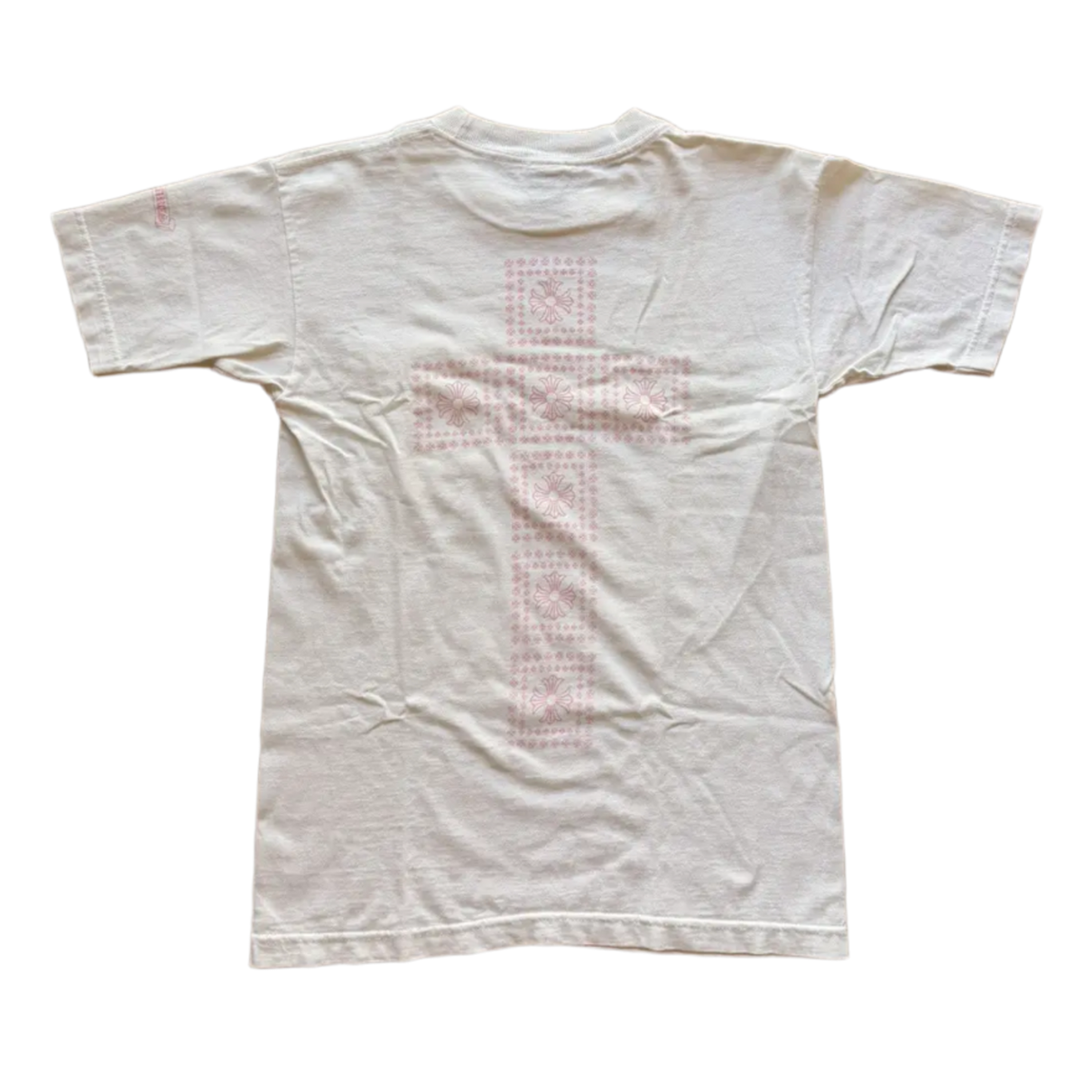 Back flat lay view of the cream vintage Chrome Hearts graphic t-shirt, highlighting the classic relaxed drape across the shoulders and a straight-cut lower hemline, dominated by a large, central pastel pink signature cemetery cross design motif screen-printed vertically down the center spine panel.