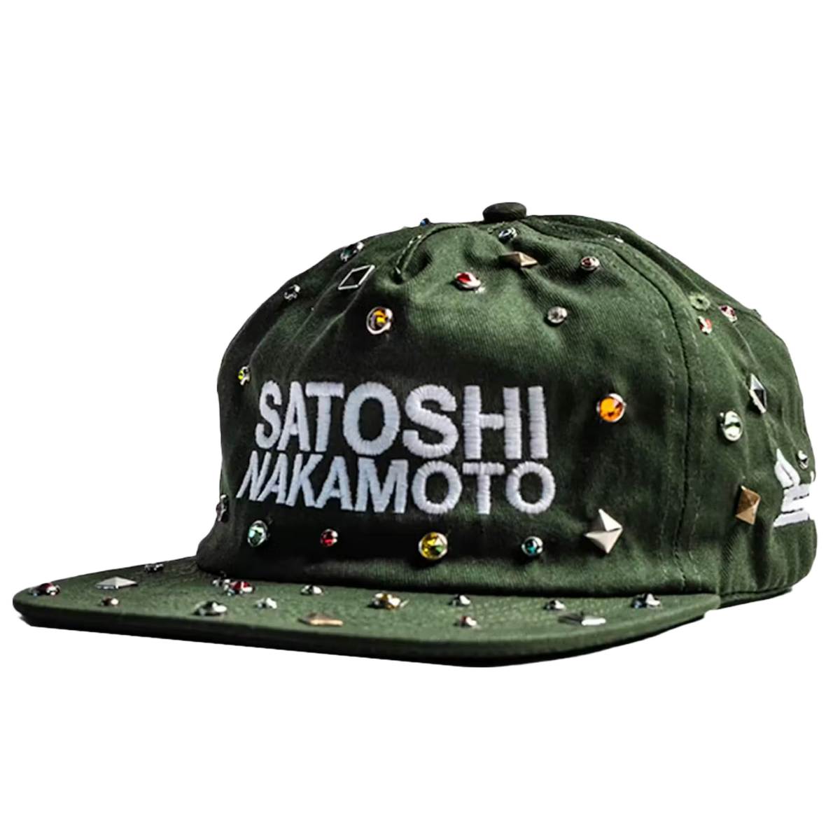 A three-quarter front angled studio layout view of the Satoshi Nakamoto x Sicko collaborative hat, showcasing a structured six-panel snapback cap profile crafted from a premium olive-green woodland camouflage cotton twill canvas, heavily embellished across the front crown and curved brim with an aggressive, scattered arrangement of polished silver metallic punk metal cone studs, and dominated by thick white embroidered block lettering on the center face reading 'SATOSHI NAKAMOTO' layered over Sicko's signat