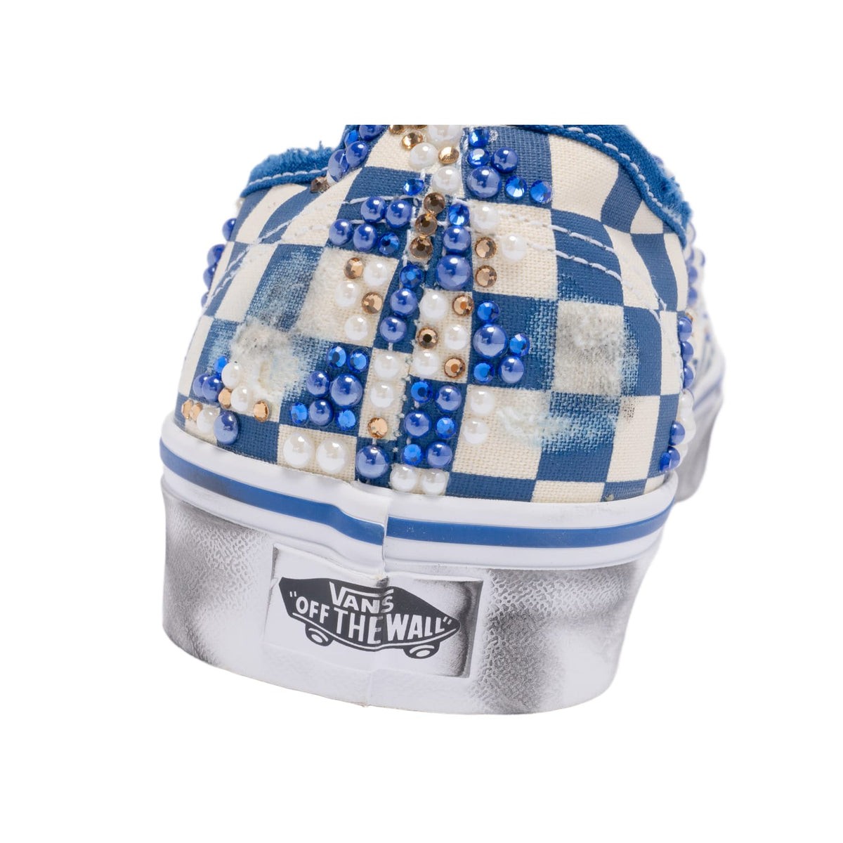 An alternate angled close-up view of the rear heel counter from a single shoe, showcasing the continuous vertical blue checkerboard canvas geometry, a white canvas loop pull tab, and the micro-textured texture of the rubber heel badge.