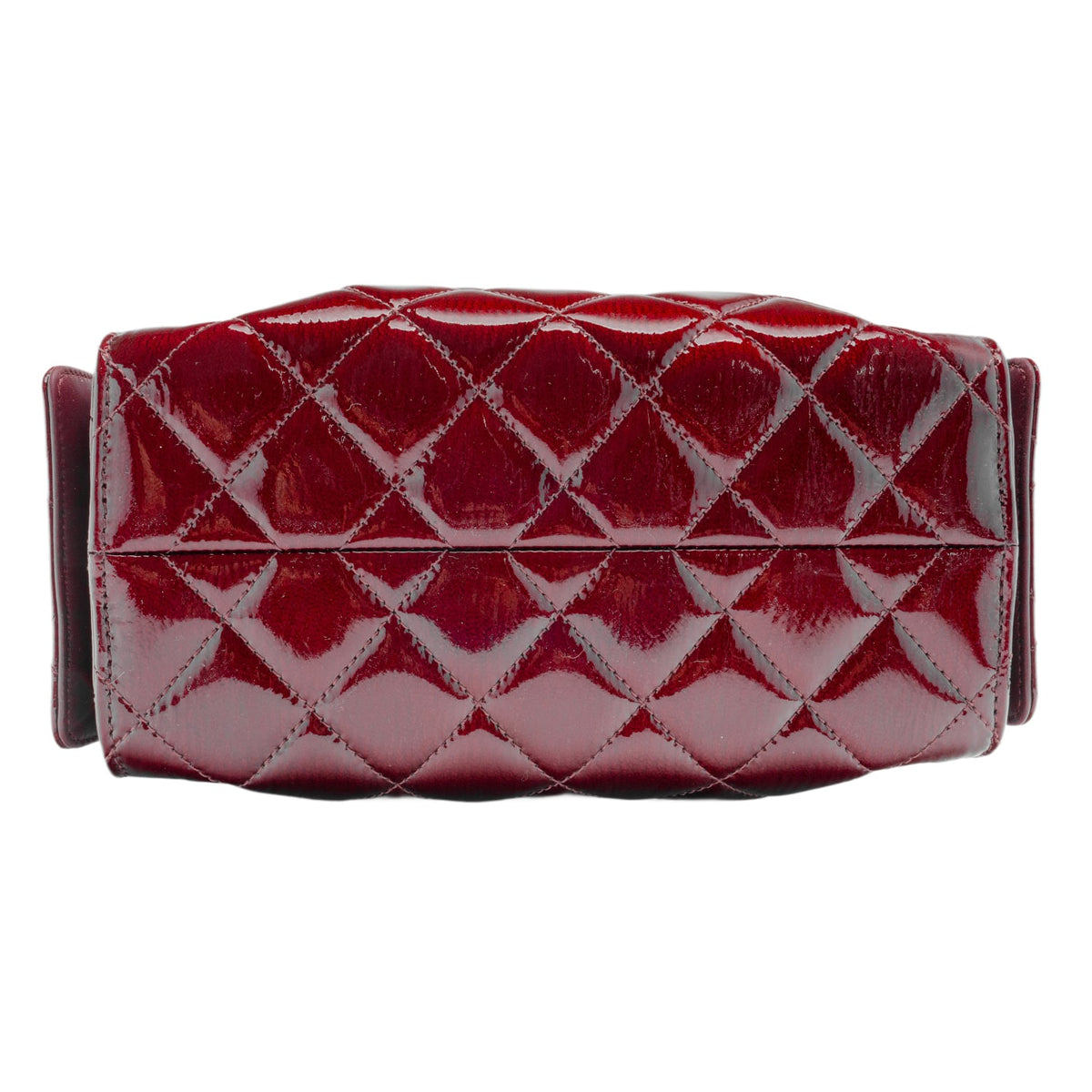 A top-down layout view focusing on the base panel of the Chanel handbag, highlighting the seamless continuation of the diamond-quilted pattern across the bottom surface, clean tonal border stitching, and the flexible grain structure of the glossy burgundy leather.