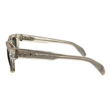 A side profile view of the Chrome Hearts 'Dick Fitzener' sunglasses, emphasizing the translucent clear acetate arm construction, the structural wire core visible inside, and the intricate sterling silver hardware embellishments decorating the hinge area.