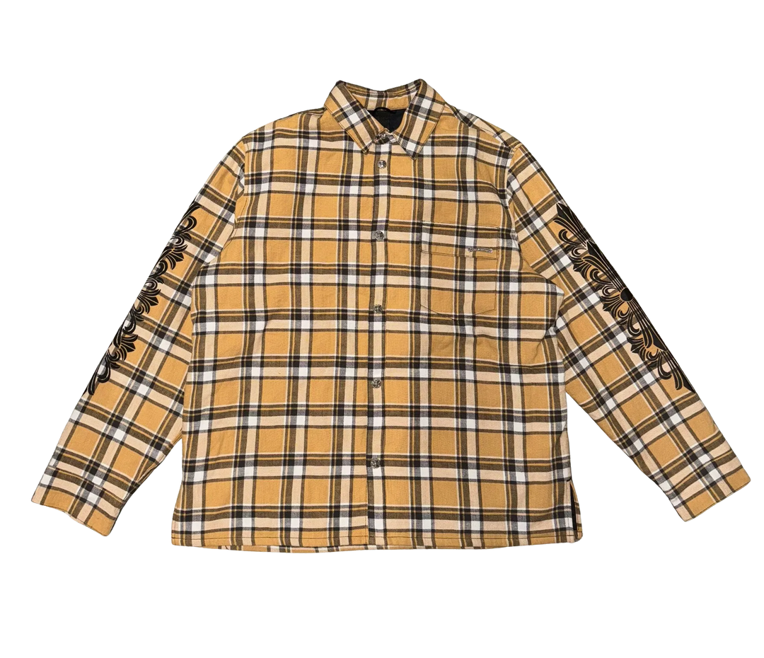 Front flat lay view of the Chrome Hearts shirt jacket in a heavyweight brushed cotton flannel, showcasing a traditional tan, black, and white plaid check pattern, a structured fold-over pointed collar, a full-length hidden center button placket, long relaxed sleeves with buttoned cuffs, a straight lower hemline, and a relaxed boxy tailoring layout.