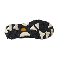 A full view of the underside of the shoe, showcasing the heavy-duty high-traction rubber outsole layout featuring an aggressive, organic multi-directional lug pattern in a striking marbled black-and-cream camo colorway, accented by a solid black structural midfoot shank plate for technical trail stability.