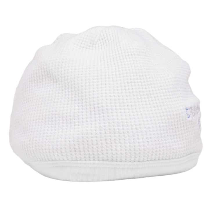 A clean side profile view of the white cotton skull cap beanie, highlighting the uniform textured stitch pattern and the low-profile streetwear silhouette.
