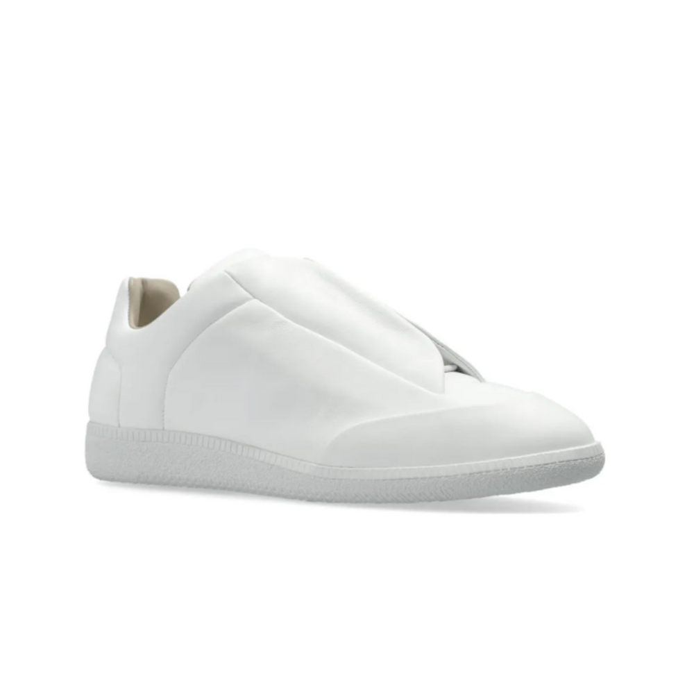 A lateral three-quarter angled view of the white Maison Margiela Future Low sneaker resting flat, highlighting the fluid, clean lines of the smooth leather shroud panels, the protective wrapped toe box bumper, and the elegant, low-profile collar transition line.