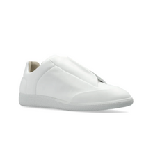 A lateral three-quarter angled view of the white Maison Margiela Future Low sneaker resting flat, highlighting the fluid, clean lines of the smooth leather shroud panels, the protective wrapped toe box bumper, and the elegant, low-profile collar transition line.