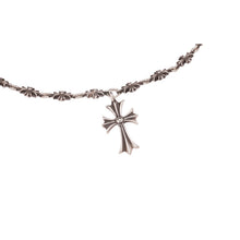 A close-up angled view of a section of the 'Tiny E' necklace laid horizontally, highlighting the precise connection points between the links and the clean drop profile of the central dangling cross pendant.