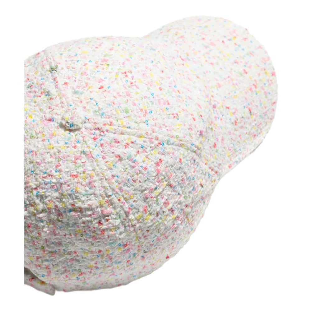 An angled side profile view of the Chanel multicolor tweed cap resting flat, highlighting the thick woven texture of the luxury fabric across the structured crown panels and along the curved bill.