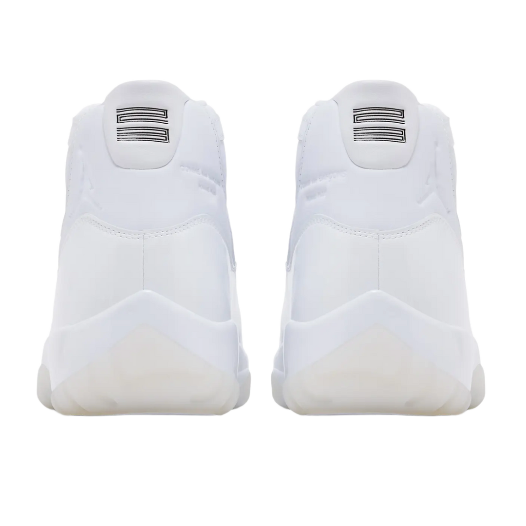 A back-facing view of both white Jordan 11 x Comme des Garçons sneakers, featuring the smooth white leather heels with debossed tonal Jumpman logos, white leather pull tabs, and white rubber outsole pods.