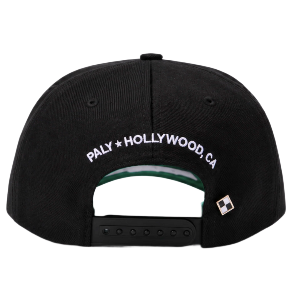 A straight-on rear view of the black Paly canvas cap resting flat, highlighting the low-profile crown posture and uniform panels, featuring an adjustable fabric strap closure with a metallic slider buckle, accented cleanly by white embroidered branding text reading 'PALY HOLLYWOOD CA.' stitched across the rear opening arc.