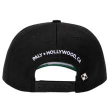 A straight-on rear view of the black Paly canvas cap resting flat, highlighting the low-profile crown posture and uniform panels, featuring an adjustable fabric strap closure with a metallic slider buckle, accented cleanly by white embroidered branding text reading 'PALY HOLLYWOOD CA.' stitched across the rear opening arc.