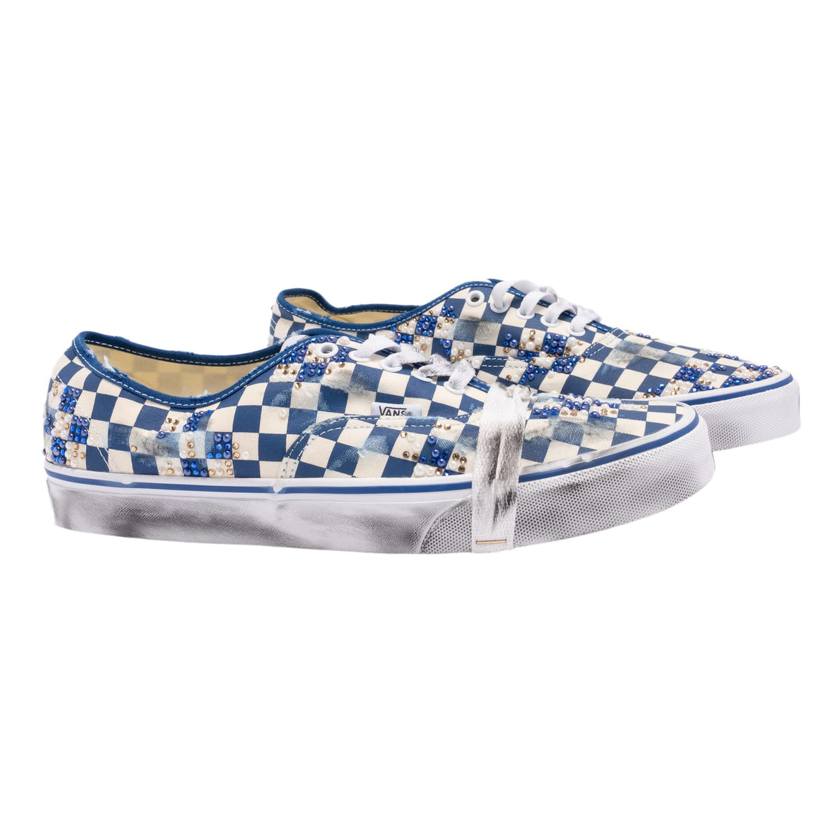 A lateral three-quarter angled view of both blue checkerboard collaborative sneakers arranged together, highlighting the pre-distressed canvas panel contours, white contrast perimeter stitching, clean metal eyelets, and the distressed structural foxing wrap running around the toe boxes.