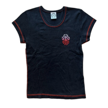 Front flat lay view of the vintage Chrome Hearts women's baby tee in a soft, premium washed black cotton knit, showcasing a form-fitting cropped y2k silhouette, a wide scooped neck collar with a white internal brand label, short sleeves highlighted by vibrant contrast red flatlock coverstitching along the hems, and a small red and white graphic emblem screen-printed over the left ribcage.