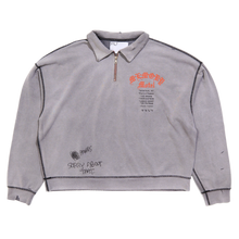 Front flat lay view of the Paly 'Sorry Bout That' quarter-zip sweatshirt in a sun-faded heather grey cotton, featuring an oversized boxy fit, dropped shoulders, a silver metal zipper collar, a small red chest graphic, and an illustrative black emblem printed near the bottom left hem.