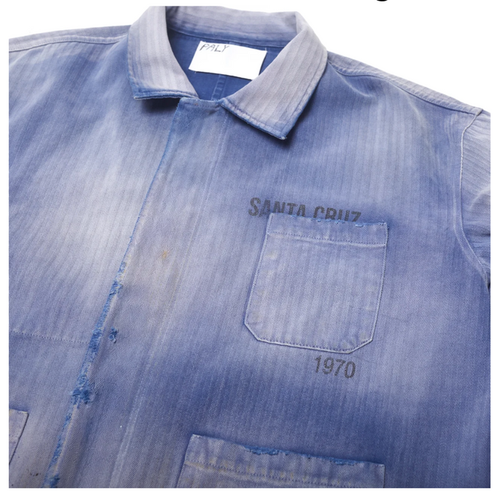 Close-up front detail of the Paly Work Shirt collar and top pocket, showing the textured herringbone cotton canvas, distressed raw-edge placket seams, and a dark 'SANTA CRUZ 1970' stamp.
