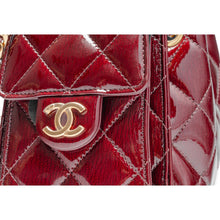 An extreme macro shot focusing on the quilted leather panels, highlighting the rich, fine-grain crinkle lines and natural leather wrinkles that give the shiny burgundy calfskin surface its distinctive textured and light-reflective depth.