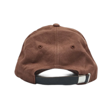 Back view of the washed brown studded cap, showcasing an adjustable black fabric strap closure with a silver metal buckle, a curved rear opening, and clean canvas panels tapering to the top crown button.