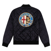 Back flat lay view of the black diamond-quilted Supreme bomber jacket, highlighting the structured outerwear volume across the shoulders and back panel, dominated by a large, intricate circular multi-colored sequin patch emblazoned across the upper back torso depicting an ornate crest design with a red cross, blue detailing, and bold typography.