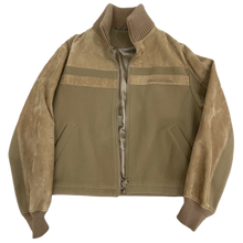 Front flat lay view of the Louis Vuitton zip-up teddy jacket in a premium camel brown suede, showcasing a relaxed collegiate varsity silhouette with an olive-green contrast fabric lower torso panel, horizontal suede chest banding, a structured pointed collar with a silver metal front zipper track, slash side hand pockets, and matching thick camel brown elasticated ribbed knit cuffs and lower hemline.