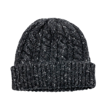 A clean profile layout view of the black and ecru Chanel knit cashmere beanie resting upright, highlighting the dense multi-directional cables and chunky ribbed texture tapering cleanly upward to a four-point crown closure, with a solid unadorned rear profile.