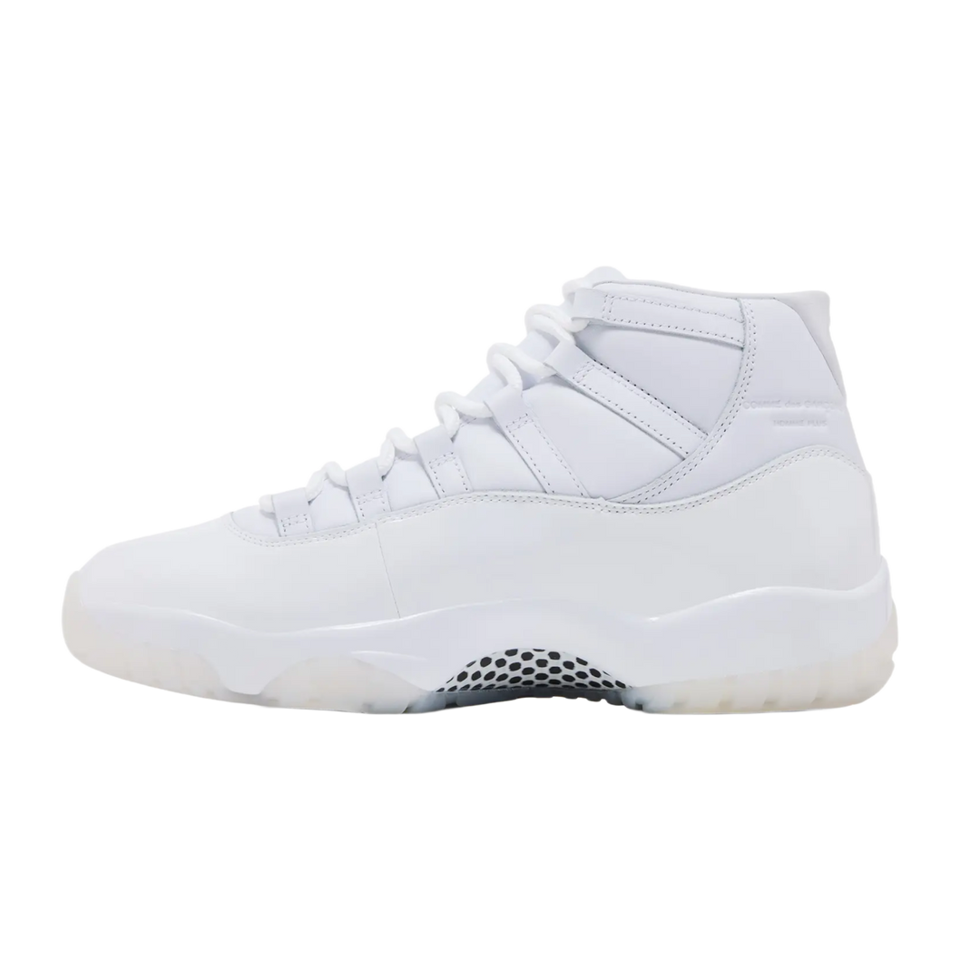 A clean lateral profile view of the all-white Jordan 11 x CDG sneaker, showcasing the high-cut patent leather mudguard wrapped cleanly around the midsole, tonal white lacing loops, and a milky semi-translucent outsole accent under the toe.