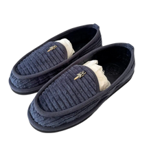 A three-quarter angled view of the navy blue Chrome Hearts quilted slippers stacked slightly together, showcasing the flexible indoor rubber outsole profile and a plush, off-white fuzzy shearling interior lining peeking out from the ankle opening.