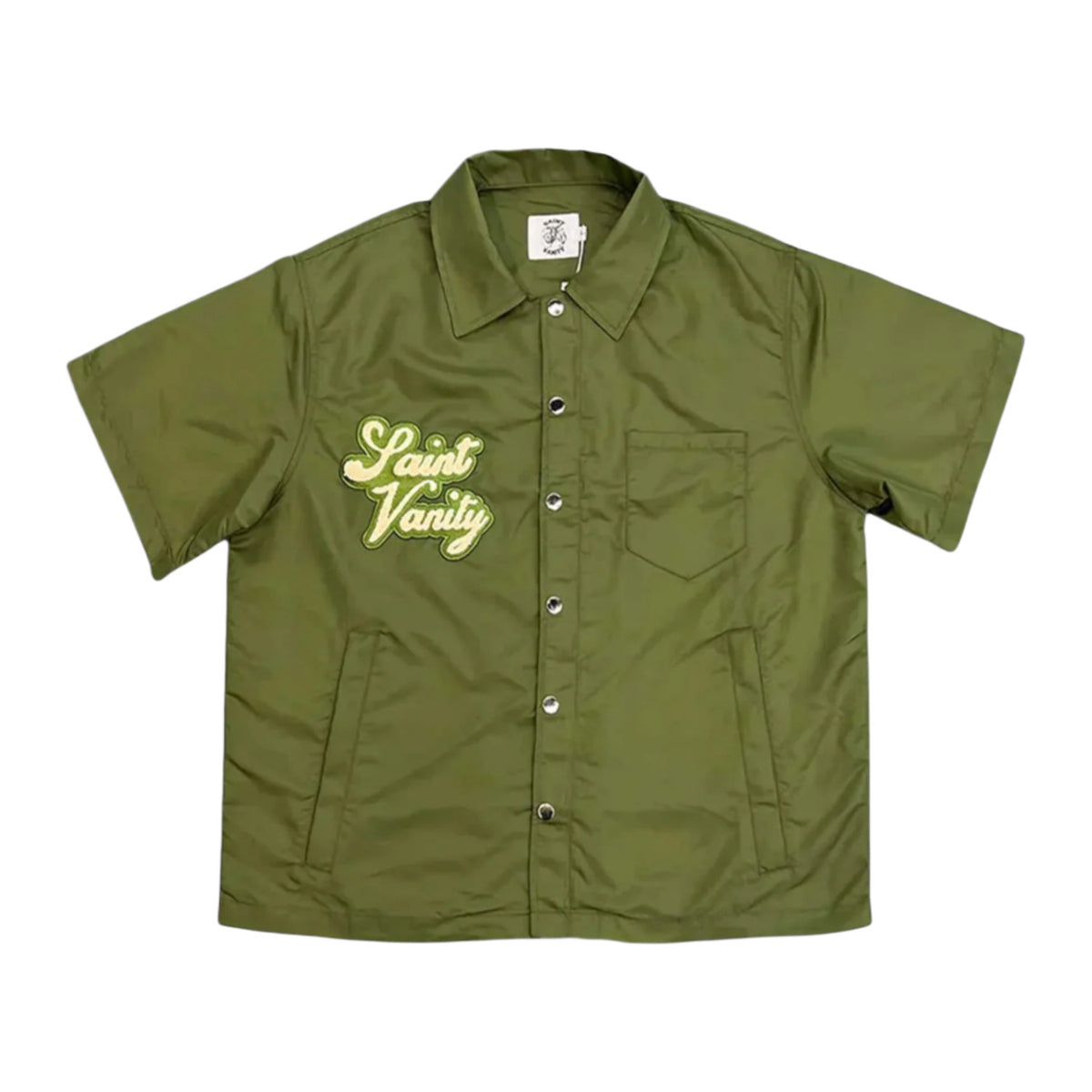 Front flat lay view of the Saint Vanity button-up shirt in smooth matte olive green technical nylon fabric, showcasing a boxy short-sleeve silhouette, a structured pointed camp collar, a full-length olive button front closure placket, a square flat hemline, and elegant light yellow cursive script branding reading 'Saint Vanity' embroidered directly over the right chest.