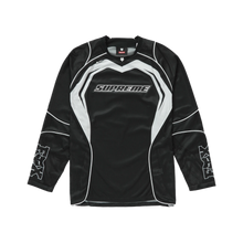 Front flat lay view of the Supreme x Fox Racing long-sleeve jersey in lightweight black technical performance mesh, showcasing an athletic motocross silhouette with dynamic white and grey accent panels slicing across the shoulders and upper sleeves, a ribbed V-neck collar, tight athletic wrist cuffs, and a horizontal co-branded box logo graphic printed squarely on the center chest.