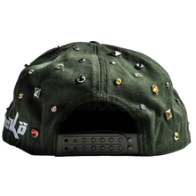 An angled rear view of the green camouflage Satoshi Nakamoto x Sicko studded hat resting flat, highlighting the curved crown architecture, tonal ventilation eyelets, and the adjustable dark green multi-notch plastic snapback enclosure for a customizable fit, accented by a continuation of the scattered silver metallic stud clusters running across the side and rear panel walls.