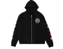 Front flat lay view of the Chrome Hearts zip-up hoodie in heavyweight jet-black cotton fleece, showcasing a relaxed boxy silhouette, a thick structured drawstring hood, a silver metal center zipper track, split kangaroo pouch pockets, a small white signature horseshoe monogram printed on the left chest, and a vibrant multicolor gradient layout of gothic branding graphics running down both sleeves.