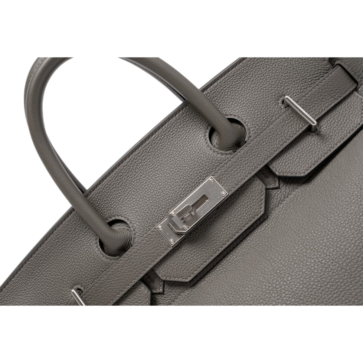 A detailed close-up shot of the open front flap draped backward, highlighting the loose leather sangles, the pristine metallic finish of the open palladium turn-lock spindle, and the fine metallic foiling stamp reading 'HERMÈS PARIS MADE IN FRANCE'.