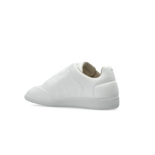 A flat medial side profile view of the white leather sneaker, emphasizing the seamless, unadorned structural panel design stretching across the inner foot walls, the geometric precision of the leather overlay sections, and the uniform tone of the matching white cupsole.
