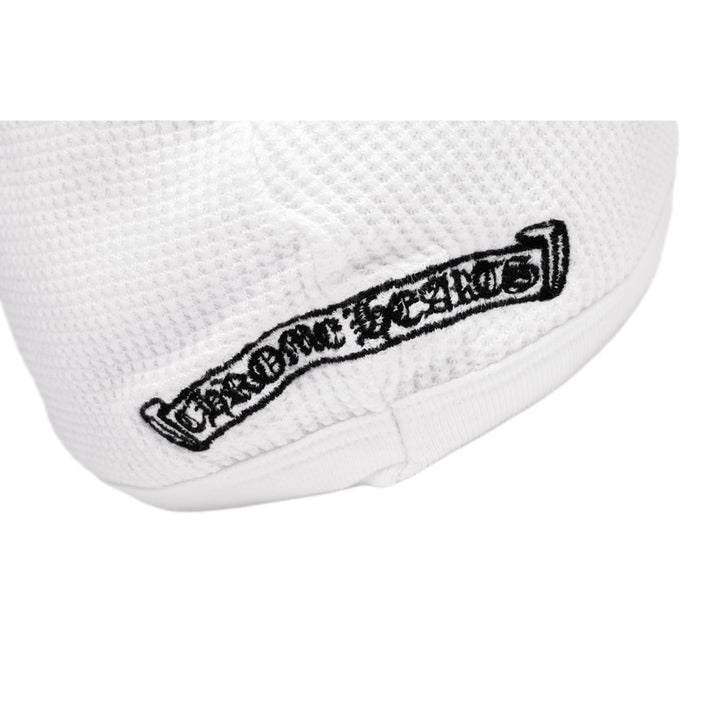 Macro detail of the black Chrome Hearts scroll banner graphic, showcasing the crisp gothic lettering and floral borders contrasting against the white waffle-knit pattern.