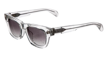 A three-quarter front view of the Chrome Hearts 'Dick Fitzener' sunglasses, showcasing a modern translucent clear acetate frame with dark grey tinted lenses, highlighted by detailed sterling silver floral cross hardware embedded at the temple hinges.