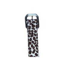 A close-up view of the animal print belt laid flat, showcasing the contrasting dark brown cheetah spots over the textured cream hair-on-hide fabric base, alongside the detailed silver metal roller buckle and prong enclosure.