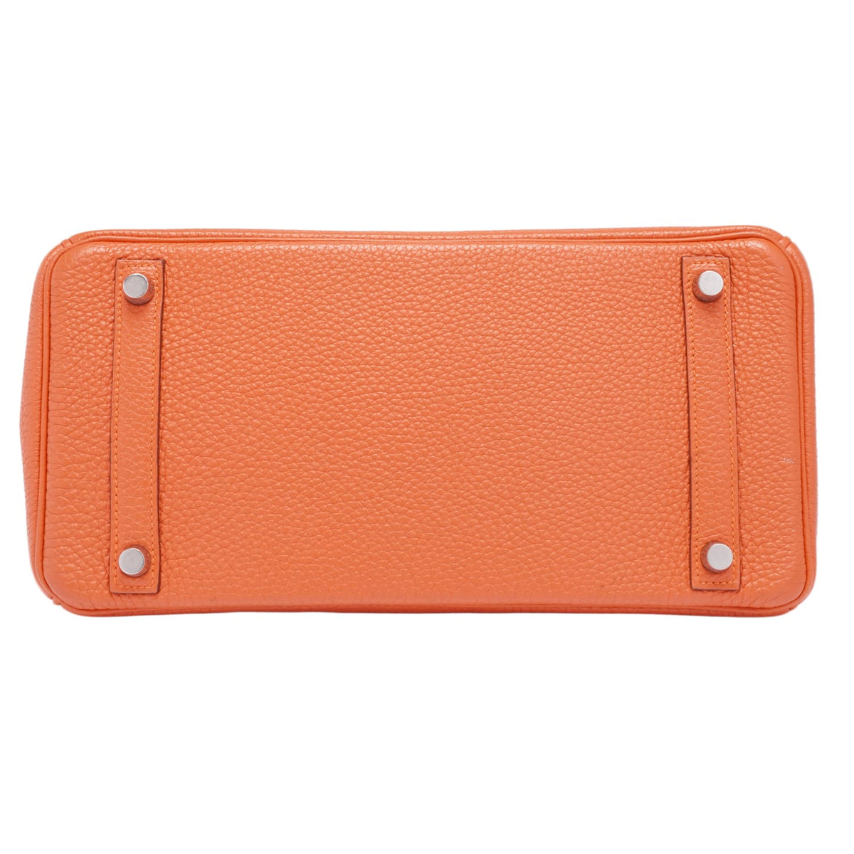 A bottom view of the base of the orange Hermès Birkin 30 bag, showcasing the protective rectangular leather paneling and four silver palladium feet studs.